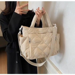 Detailed macro view of quilted cream tote bag with functional zipper pocket and texture