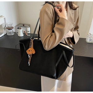 Detail of black suede tote bag with cute brown puppy charm for daily office commute