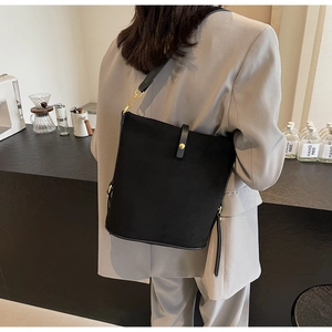 Dettaglio di una borsa tote minimalista in pelle PU nera con fibbia in metallo dorato su spalla