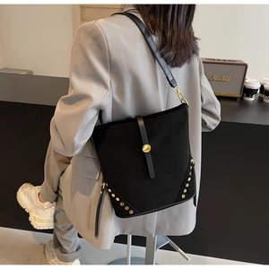 Dettaglio borsa a secchiello in PU nera con borchie dorate e tracolla in pelle chic
