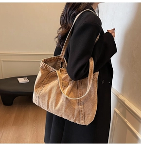 Side view of a large brown canvas tote bag with a leather brand logo tag on a female model