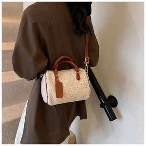 Détail du sac cylindre en peluche crème avec bandoulière en cuir marron et boucles dorées