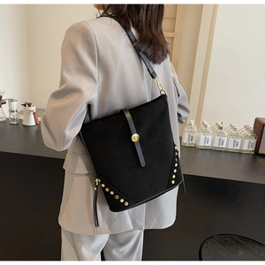 Dettaglio di una borsa tote in pelle scamosciata nera con borchie dorate su una modella