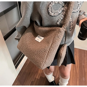 Detail view of coffee brown faux shearling bucket bag showing fluffy texture and strap