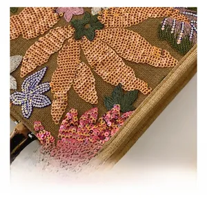 Detailed macro view of the sequin floral embroidery and linen texture on the tote bag