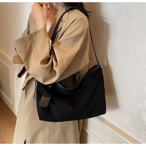Détail d'un sac fourre-tout noir minimaliste avec bandoulière en cuir sur modèle