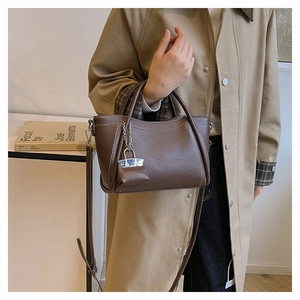 Close-up of brown litchi grain PU leather handbag with gold chain lock detail and handle