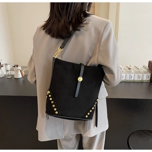 Vista posteriore di una modella con borsa a secchiello nera scamosciata e borchie dorate