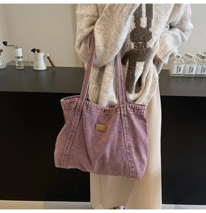 Detailed macro view of purple washed denim fabric tote bag with premium leather logo patch
