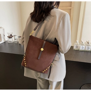 Dettaglio borsa tote in pelle PU marrone scuro opaco con rivetti dorati e chiusura in metallo
