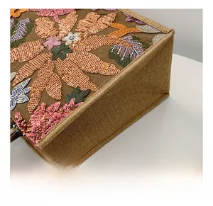 Detailed close-up of floral sequin embroidery on textured brown linen tote bag