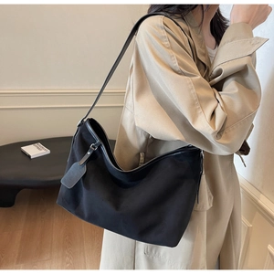 Vue détaillée d'un sac hobo noir en nylon avec lanières en cuir porté par un mannequin en décor