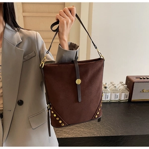 Dettaglio del tessuto scamosciato marrone e borchie dorate sulla borsa a tracolla moda