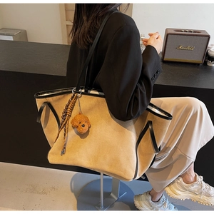 Detail of light brown suede tote bag with black leather trim and cute puppy charm