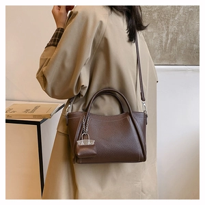 Brown lychee leather tote bag with white stitching and decorative silver lock pendant