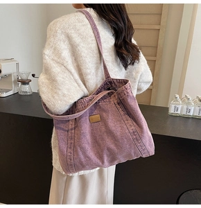 Detailed view of purple washed canvas tote bag with leather logo patch on a shoulder