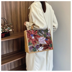 Detailed embroidery of colorful sequins and flowers on a tote bag with bamboo handles