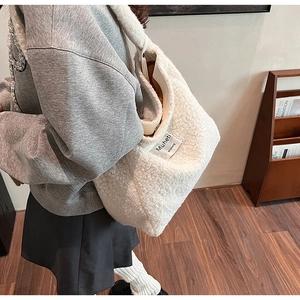 Detailed view of soft white faux fur tote bag with Muheti label worn in casual setting