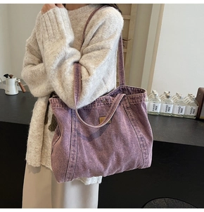 Detail of vintage purple washed denim tote bag with leather logo and magnetic snap closure