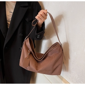 Vue détaillée du grand sac fourre-tout en daim marron porté par un mannequin chic