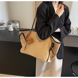 Detail of large camel faux suede tote bag with black contrast handles and dog charm