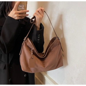 Détail du sac bandoulière en cuir PU mat marron foncé avec large sangle et étiquette