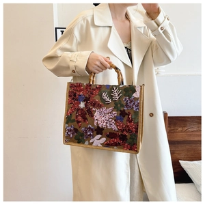 Detail of sequin floral embroidery and natural bamboo handle on ethnic linen tote bag