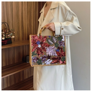 Close-up of bamboo handles and colorful floral sequin embroidery on linen tote bag