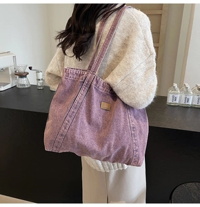 Detail of a purple canvas tote bag worn by a model in a minimalist cafe setting