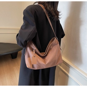 Détail d'un grand sac hobo en daim marron porté par un mannequin en style sobre