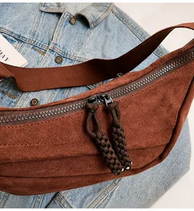Detail of coffee brown canvas crossbody bag with smooth dual zippers and woven pullers