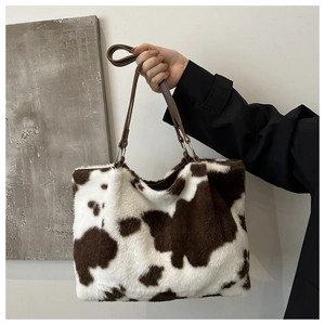 Détail du sac cabas en peluche à motif vache avec poignées en cuir et anneaux en métal