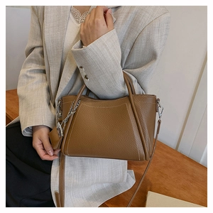 Detailed view of brown litchi grain PU leather handbag with silver chain ornament