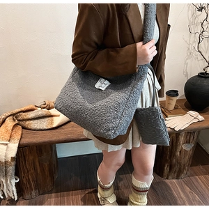 Chic grey plush tote bag with matching mini pouch in a cozy winter setting with a latte