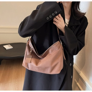 Détail d'un grand sac hobo en daim marron porté par un mannequin pour le trajet quotidien