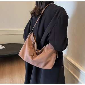 Détails de la texture du sac Hobo en daim marron avec un drapé souple et un pendentif discret