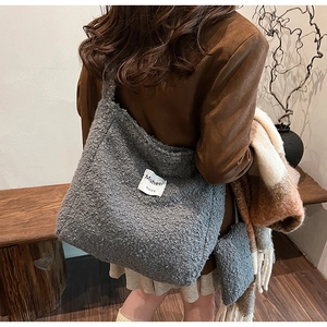 Detail view of grey plush tote bag with Muheti label and small matching pouch