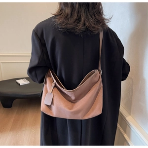 Détail du sac bandoulière en daim marron caramel montrant la sangle et le style rétro moderne