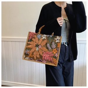 Close-up of bamboo handle tote bag with colorful flower embroidery and sequin details