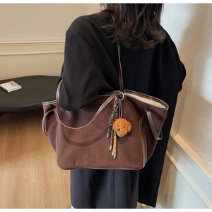 Detail of dark brown faux suede tote bag with a cute curly plush dog keychain accessory