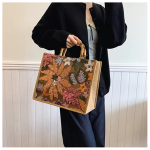 Detail of artistic floral sequin embroidery and bamboo handles on jute tote bag