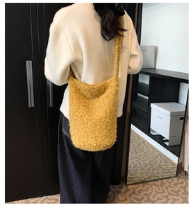 Détail du sac bandoulière en peluche jaune vif porté à l'épaule par le mannequin