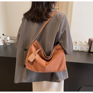 Détail d'un sac hobo en daim marron caramel porté par un mannequin en mode lifestyle