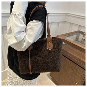 Détail du sac fourre-tout en peluche marron foncé avec anses en cuir, style automne à l'épaule