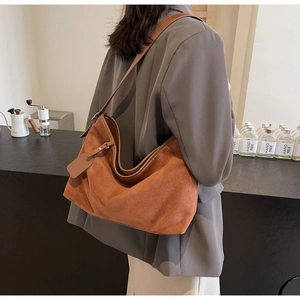 Sac fourre-tout marron caramel en cuir PU mat porté à l'épaule dans un café minimaliste