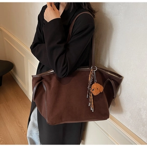 Detail of dark brown faux suede tote bag with cute teddy dog charm and braided strap