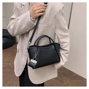 Close-up of black pebble leather tote with white contrast stitching and silver lock charm