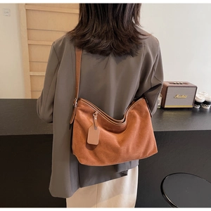 Sac bandoulière en daim marron au design vintage minimaliste porté par un mannequin en café