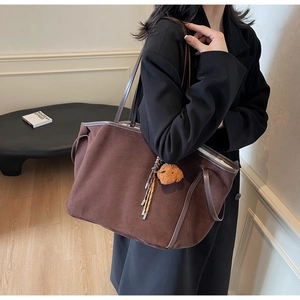 Detail of a dark brown matte faux leather tote bag featuring a cute teddy bear plush charm