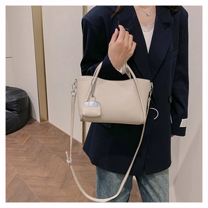 Detail of off-white lychee grain PU leather bag with mini charm and silver hardware